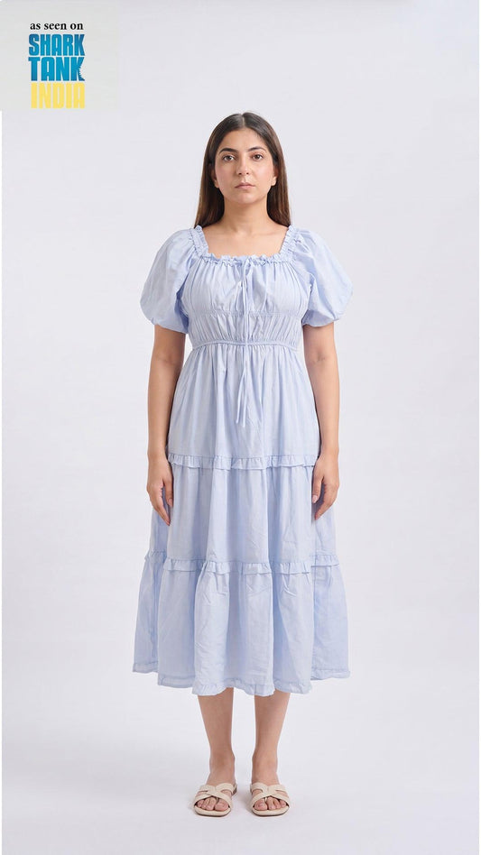 Woman wearing a light blue tiered dress on a white background with 'Shark Tank' branding.