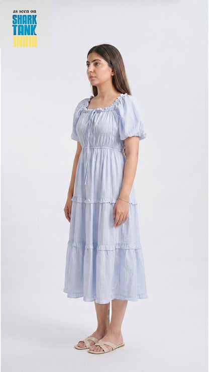 Woman wearing a light blue tiered dress on a white background