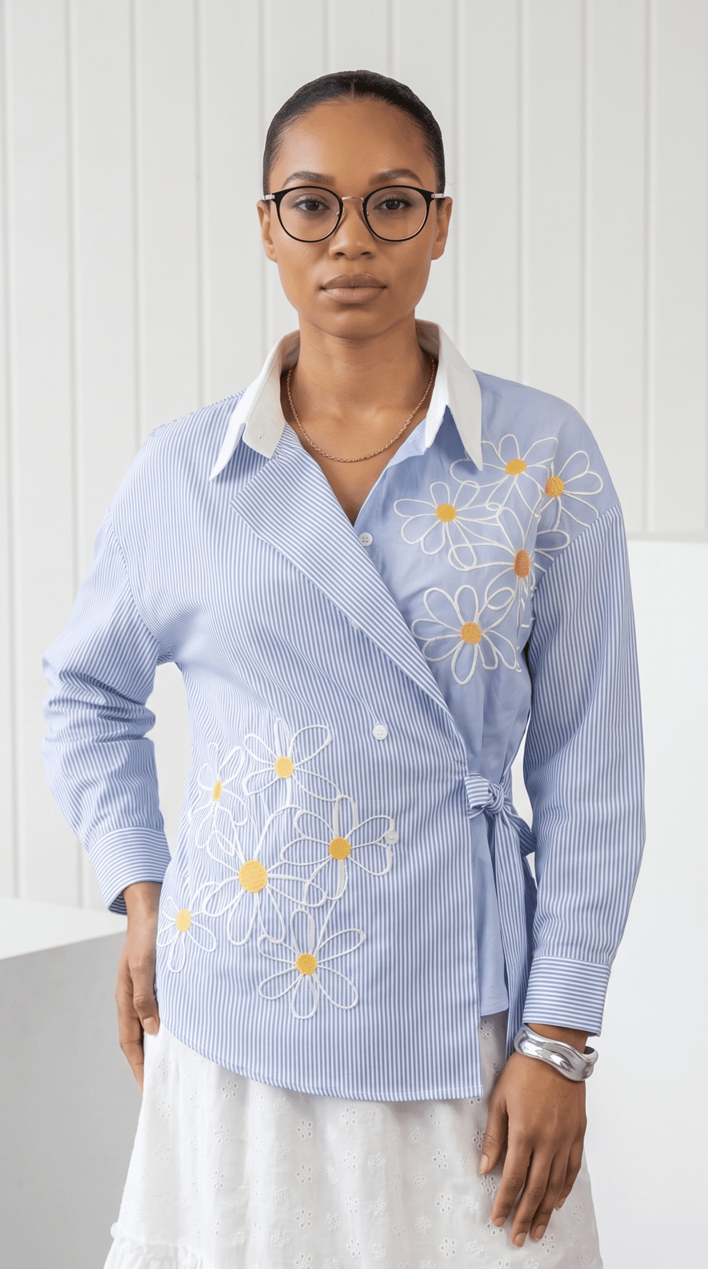 Woman wearing a light blue shirt with floral embroidery on a white background