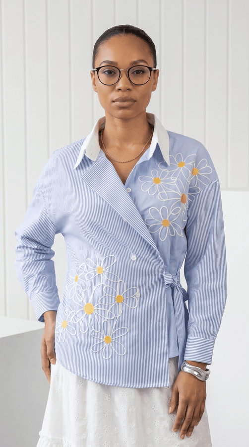 Woman wearing a light blue shirt with floral embroidery on a white background