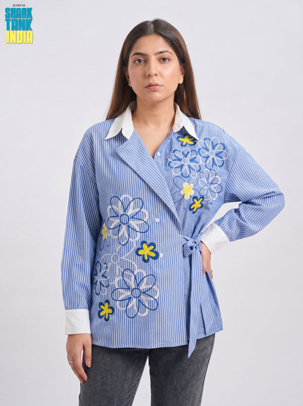 Woman wearing a blue striped shirt with floral embroidery on a white background