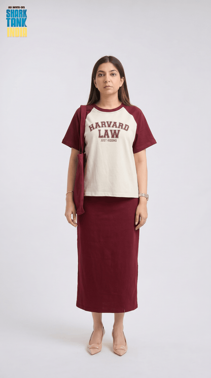 Woman wearing a maroon and beige 'Harvard Law' shirt with a long maroon skirt on a white background.