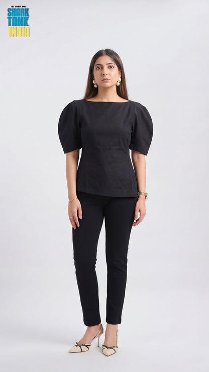 Woman wearing a black outfit with puffed sleeves on a white background