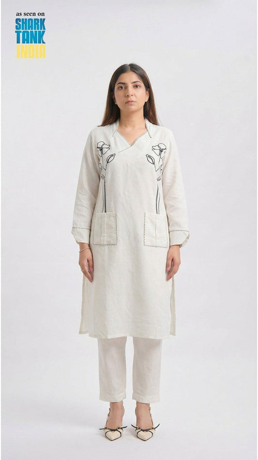 Woman wearing a white outfit with floral embroidery on a white background