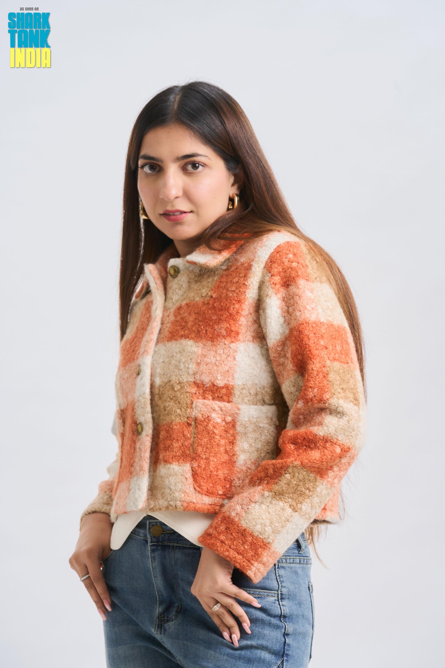 Woman wearing a plaid jacket with orange and beige pattern on a white background
