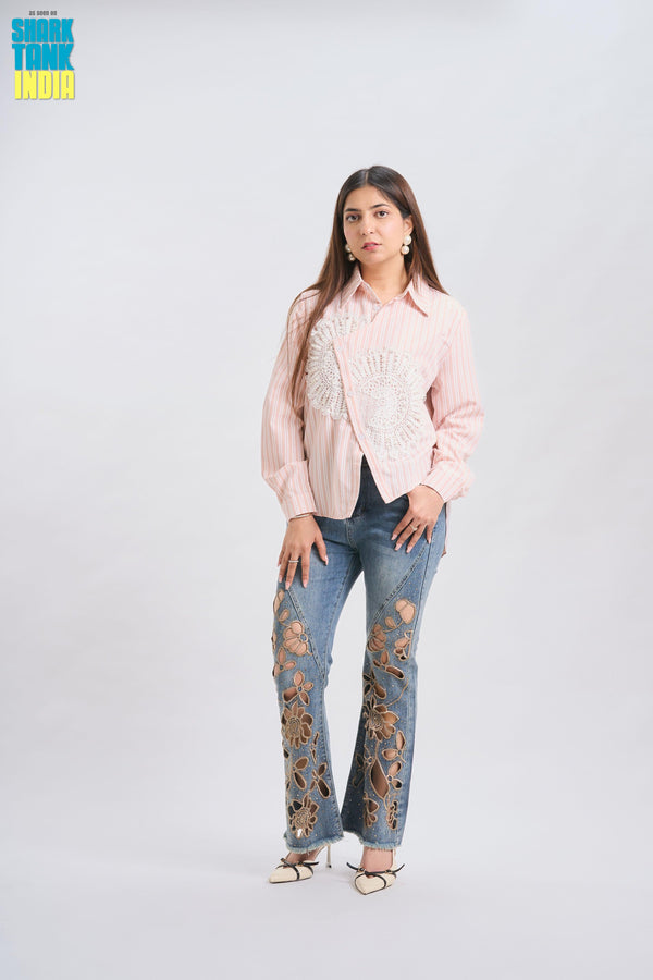 Woman wearing a light pink blouse and distressed jeans on a white background