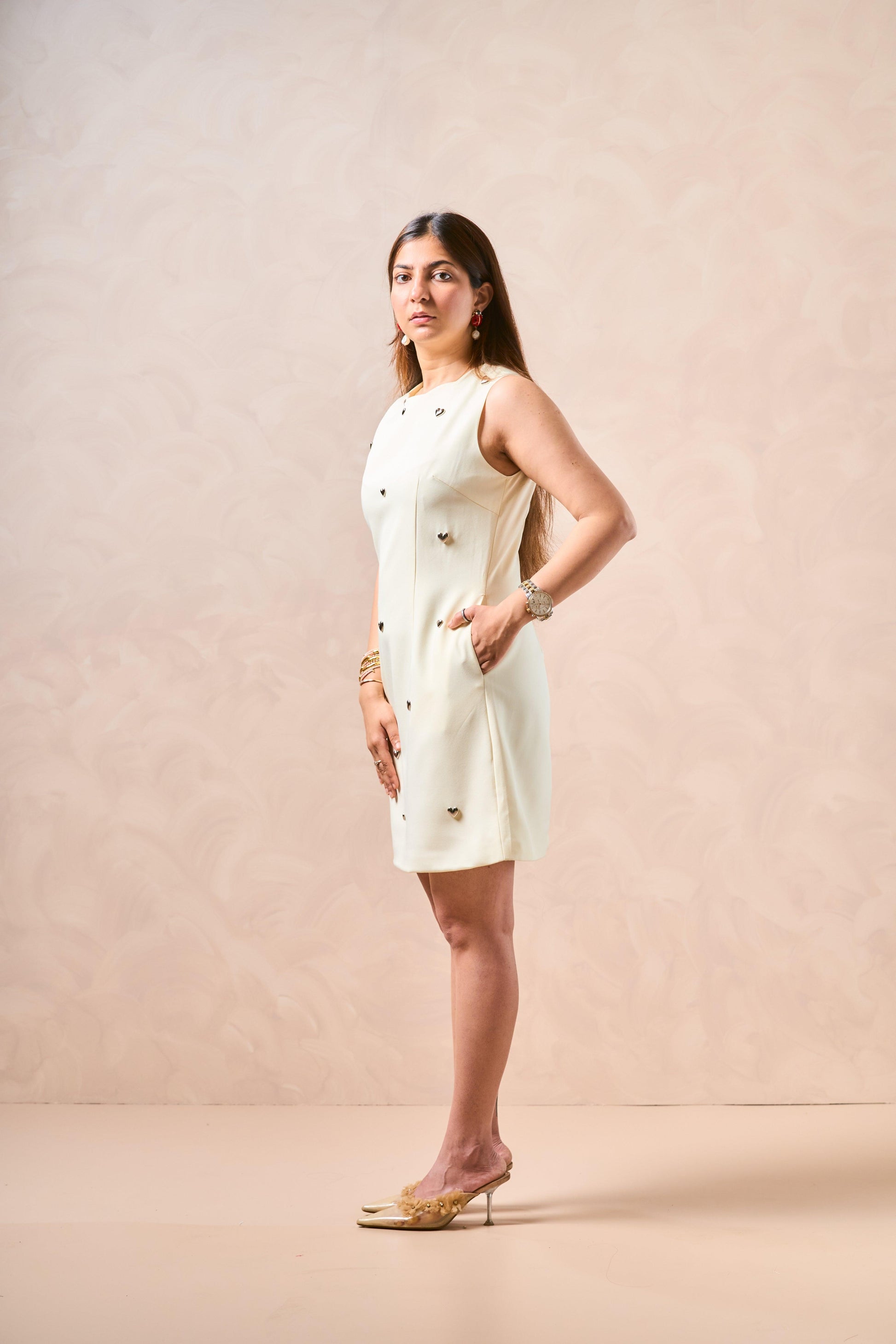Woman wearing a white dress with black polka dots against a beige background