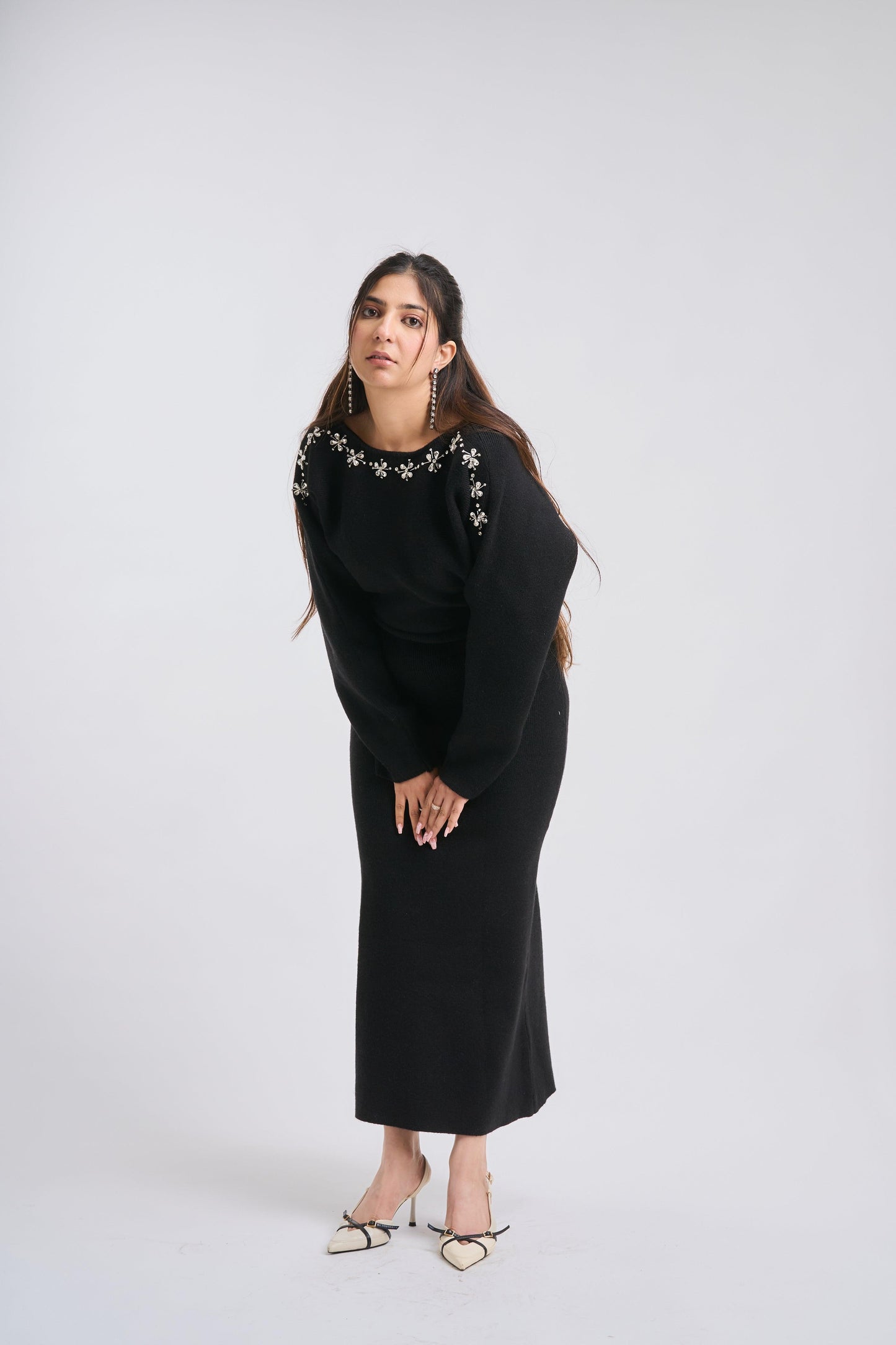 Woman wearing a black dress with floral embellishments on a white background