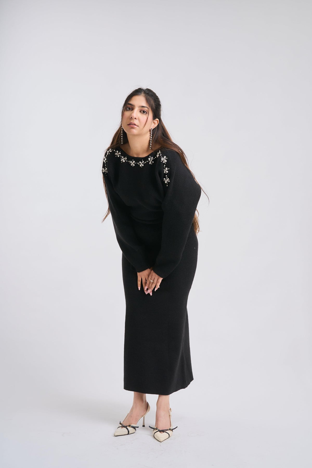 Woman wearing a black dress with floral embellishments on a white background