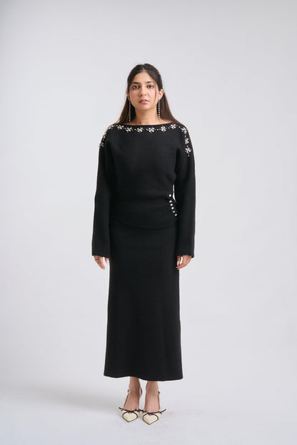 Woman wearing a black outfit with floral embellishments on a white background