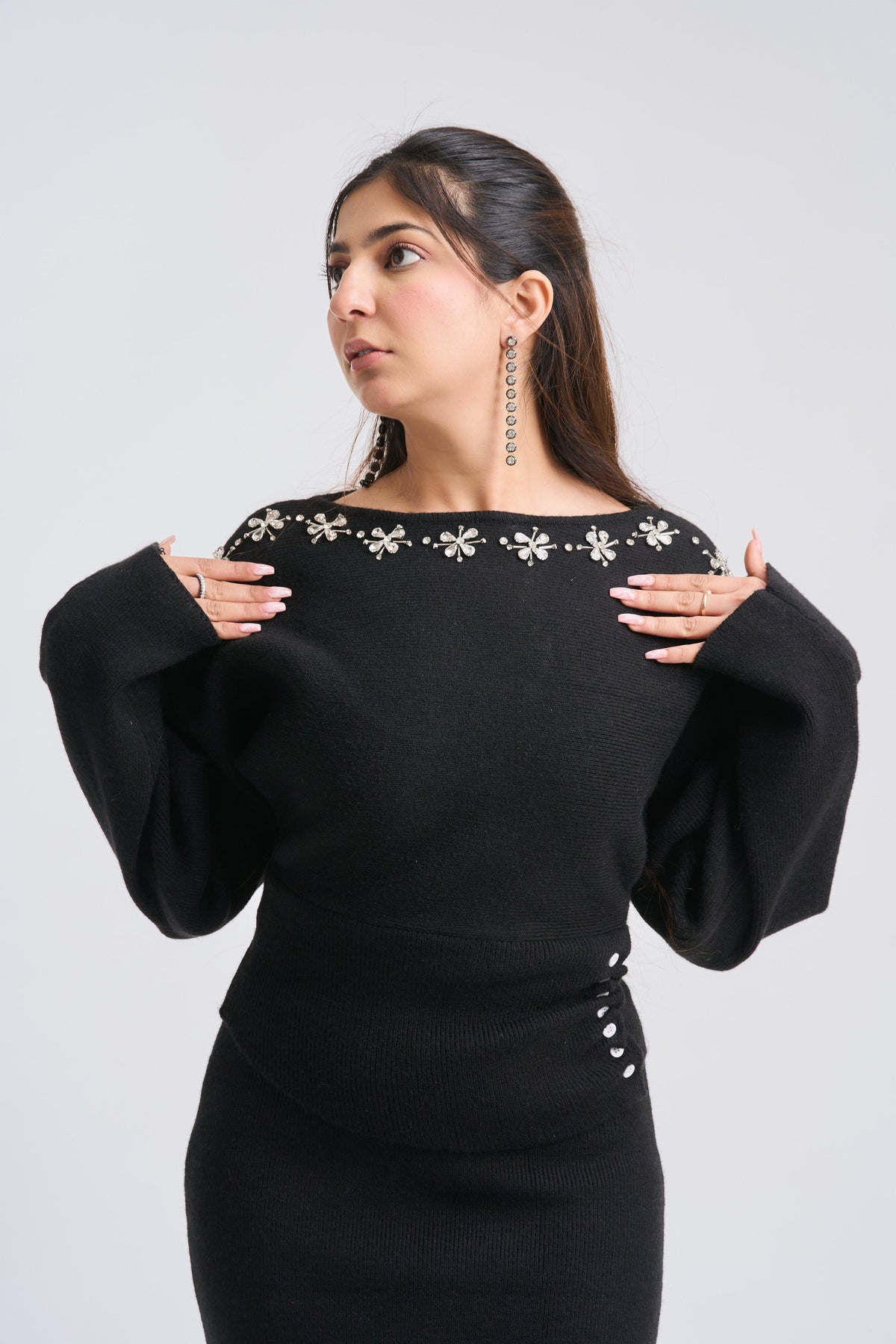 Woman wearing a black dress with floral embellishments on a white background