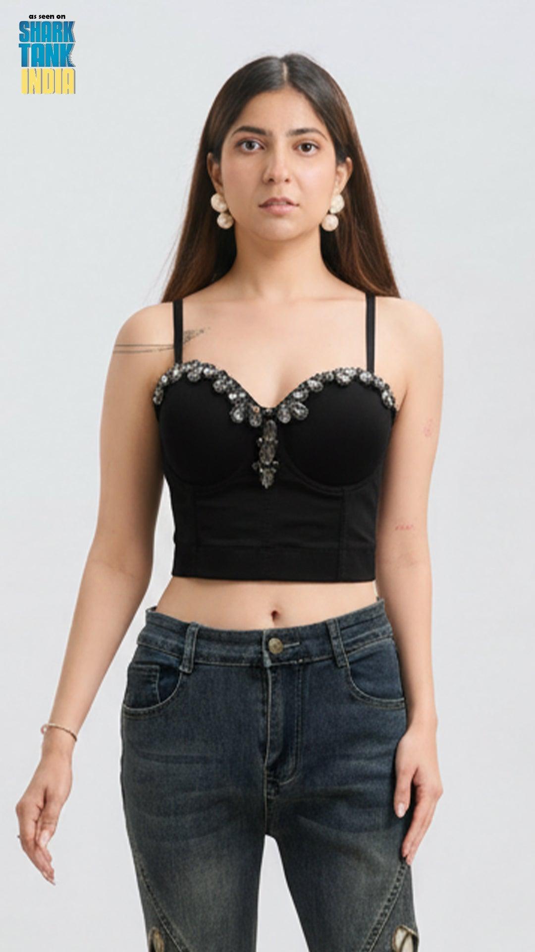 Woman wearing a black embellished top and jeans on a white background