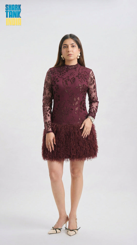 Woman wearing a burgundy lace dress with feathered skirt on a white background