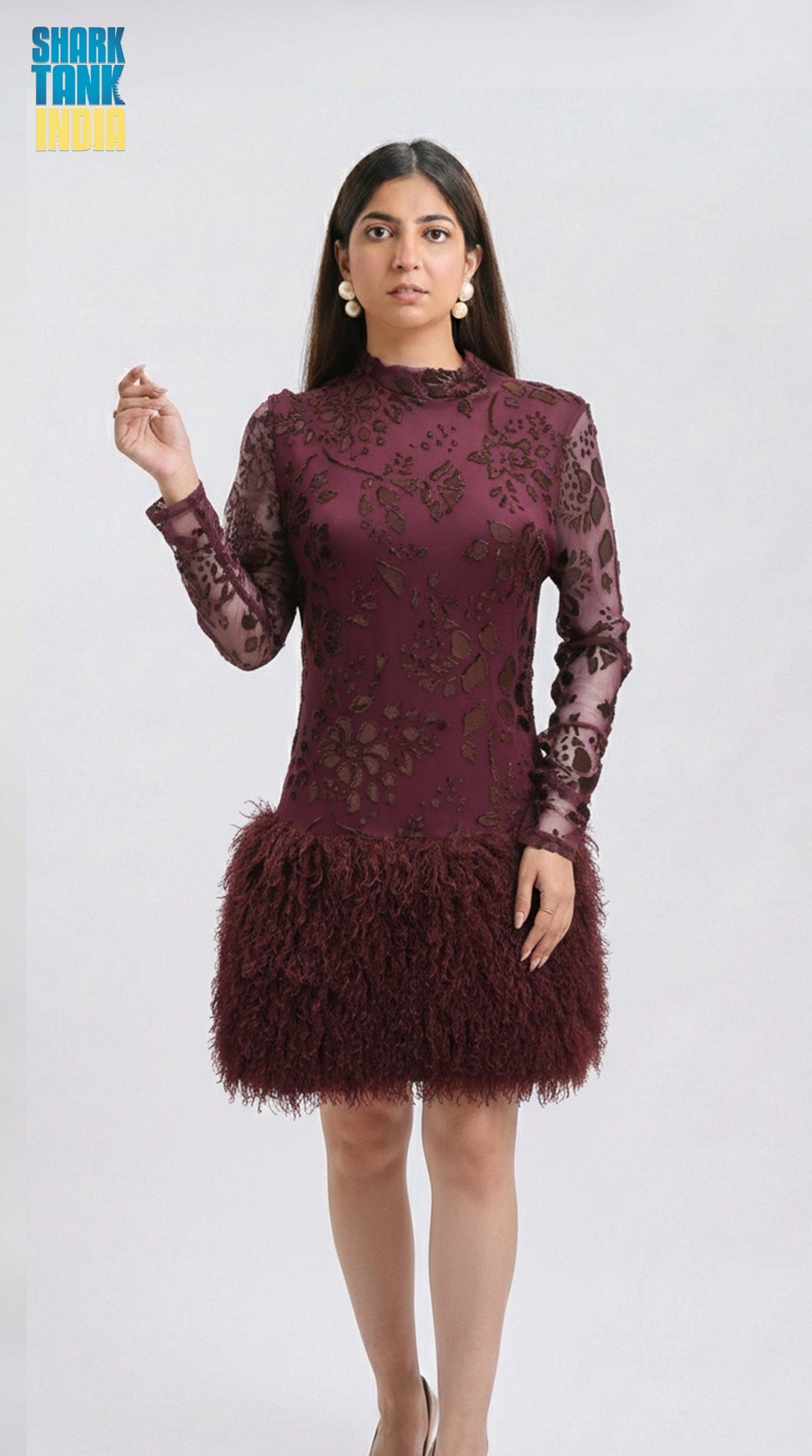 Woman wearing a burgundy lace dress with feathered skirt on a white background
