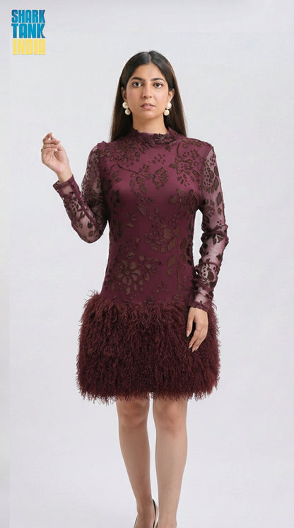 Woman wearing a burgundy lace dress with feathered skirt on a white background