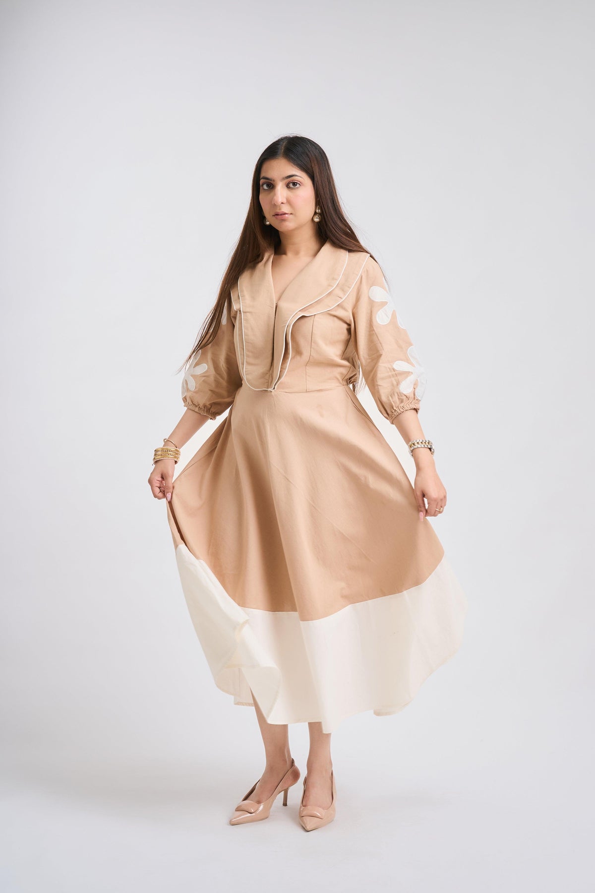 Woman wearing a beige and white dress on a white background