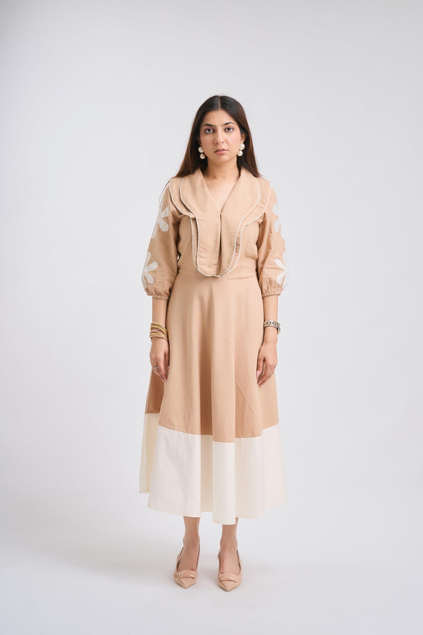 Woman wearing a beige dress with a white skirt on a white background