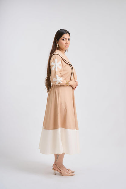 Woman wearing a beige dress with floral details on a white background