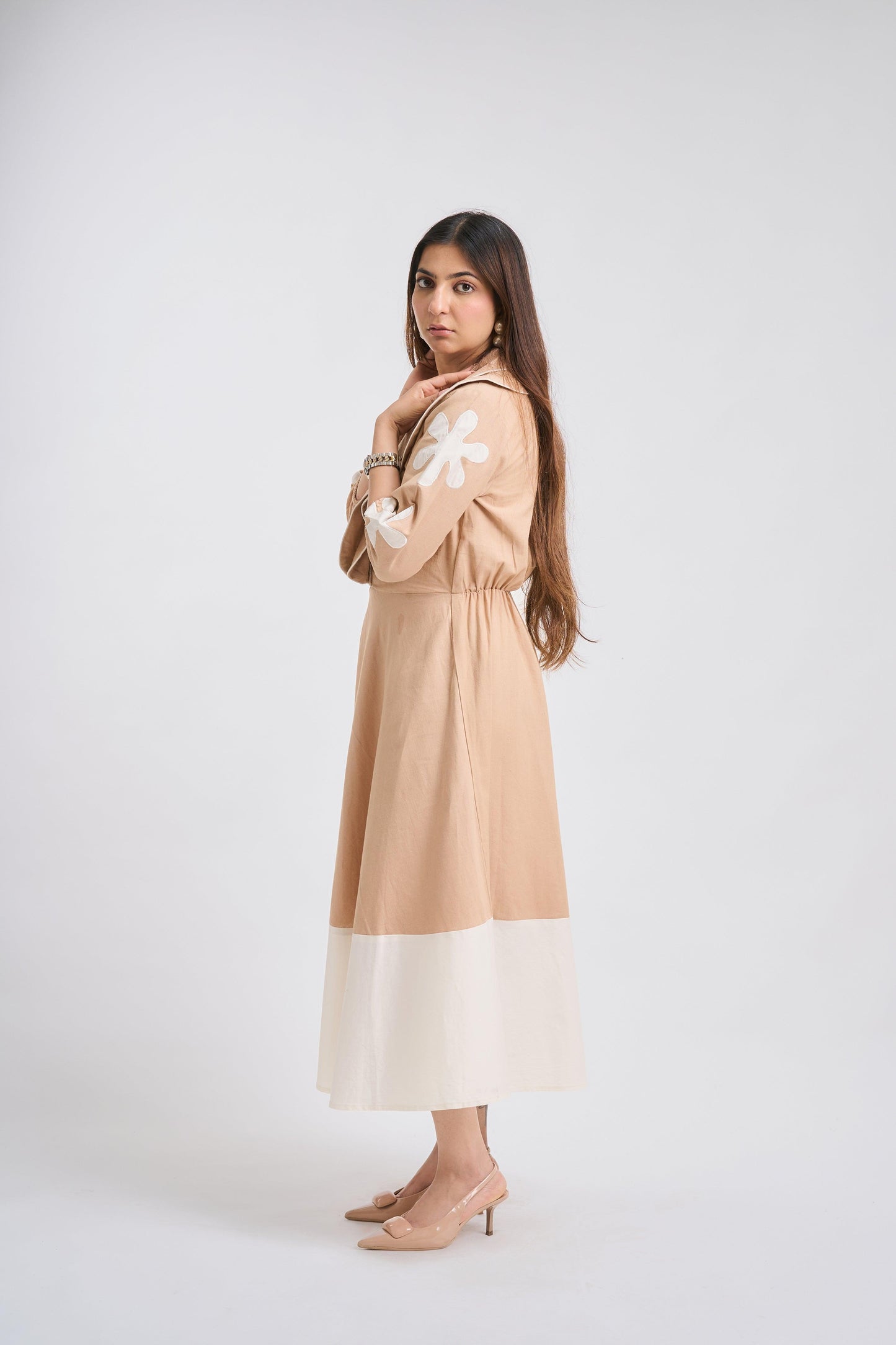 Woman wearing a beige dress with floral sleeves on a white background