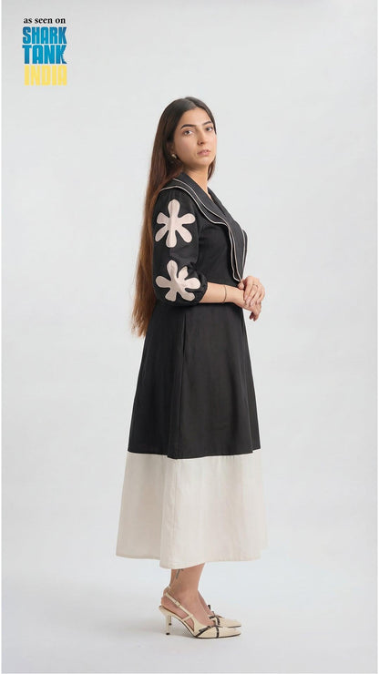 Woman wearing a black dress with white floral patterns on a white background