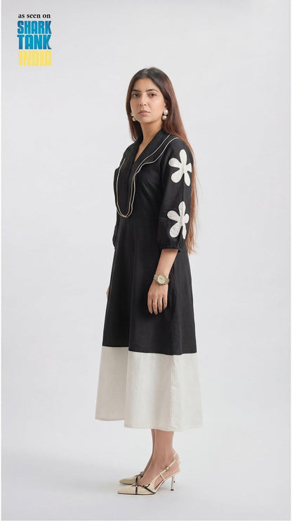 Woman wearing a black dress with white floral patterns on a white background