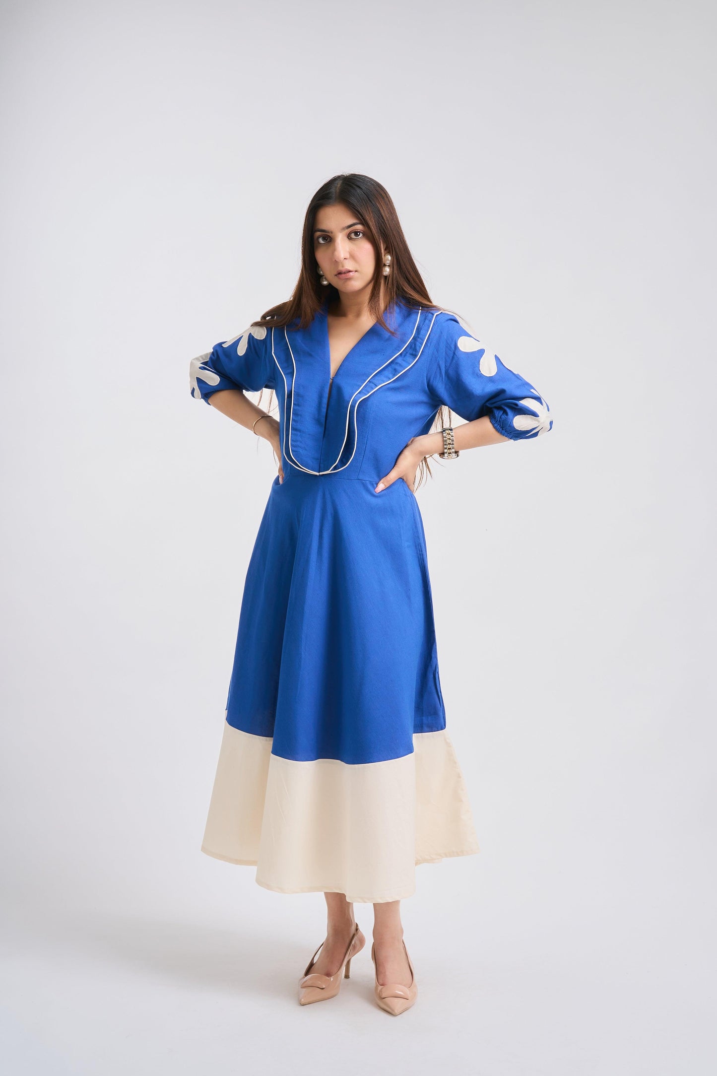 Woman wearing a blue dress with white accents on a white background