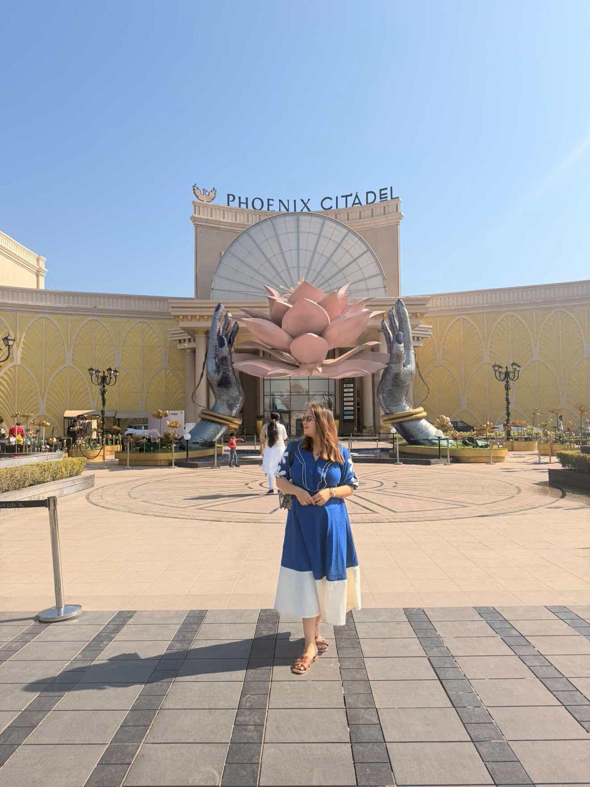 Woman in a blue dress standing in front of the Phoenix Citadel building.