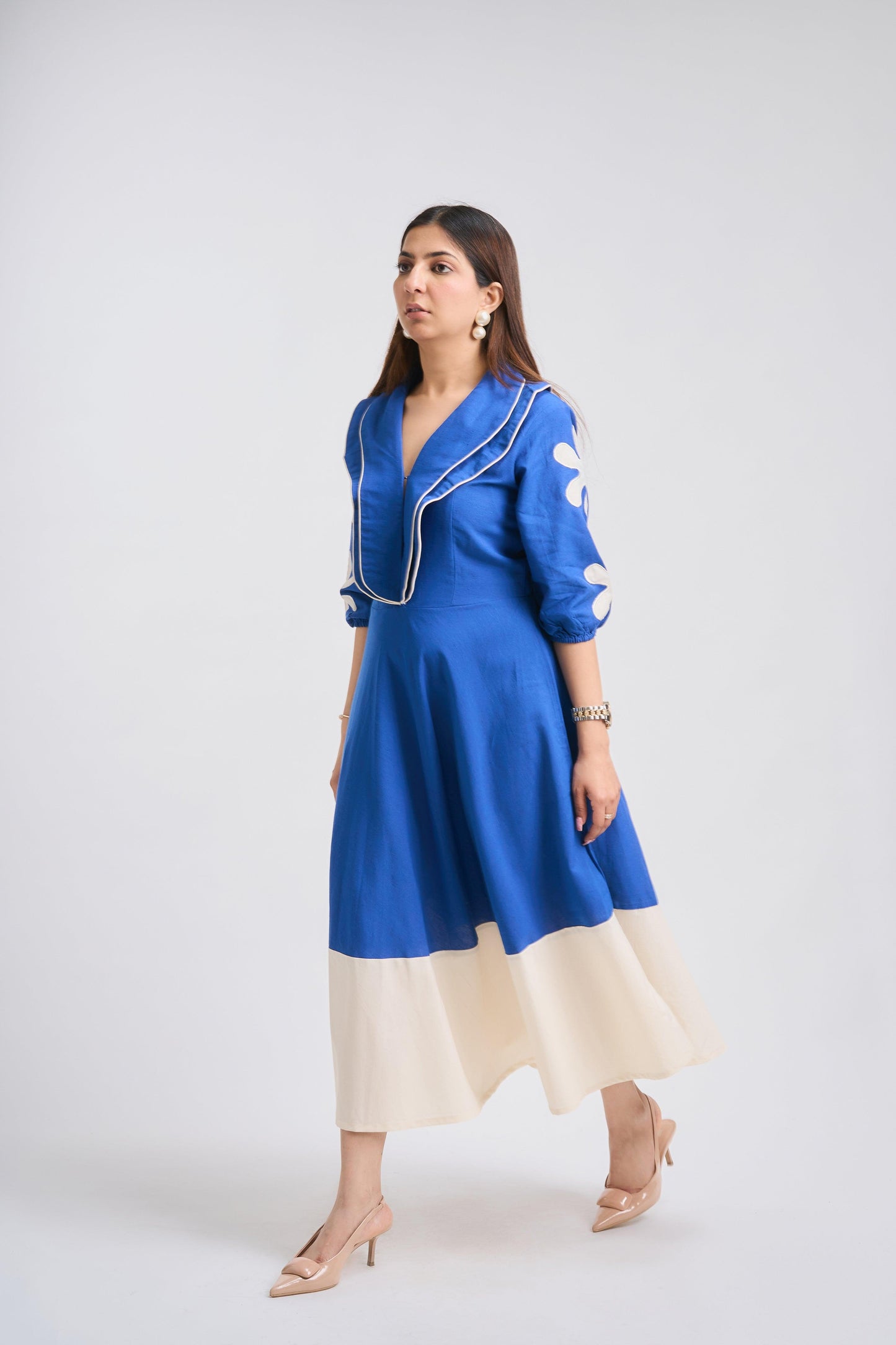 Woman wearing a blue and beige dress against a white background