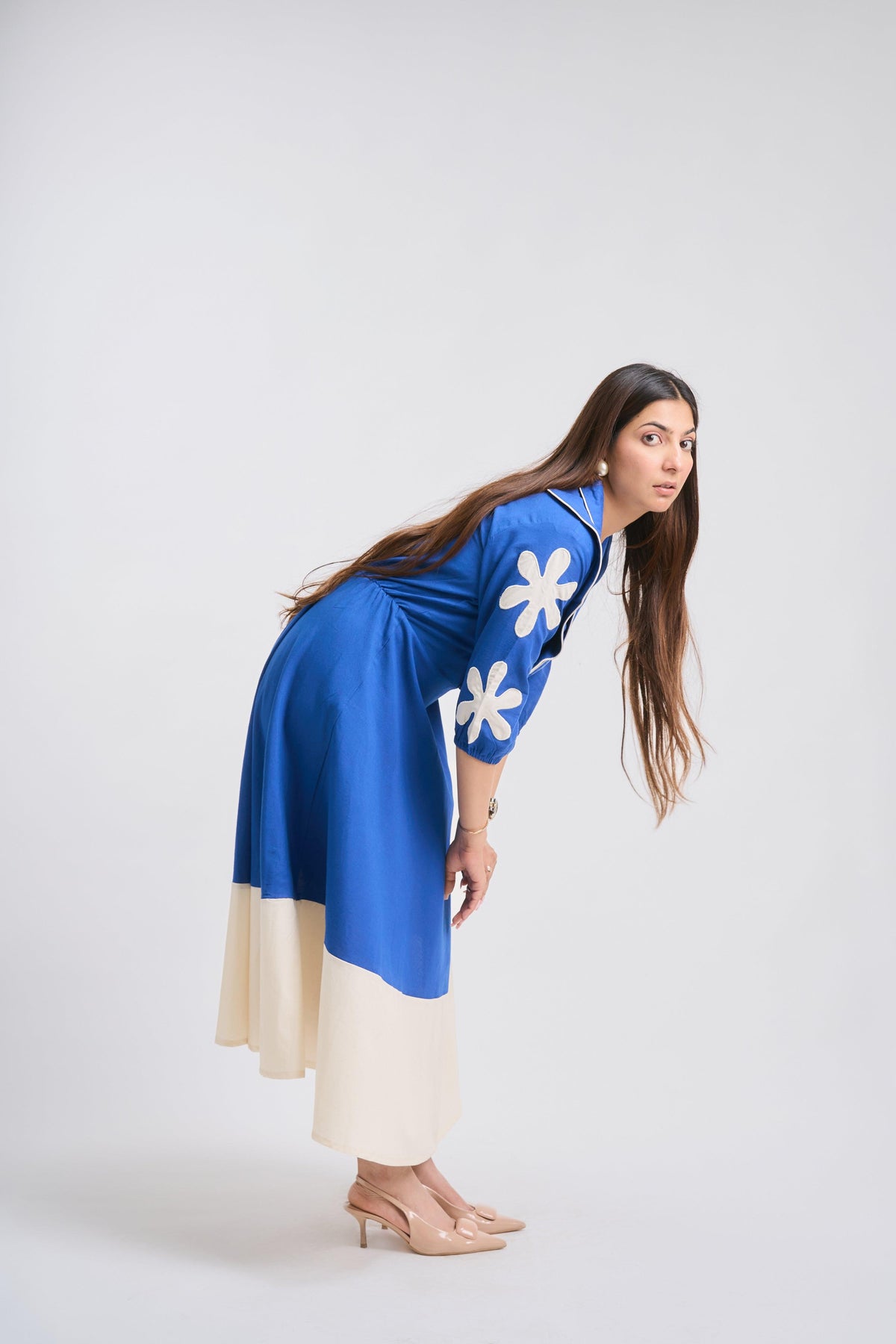 Woman wearing a blue dress with white floral patterns on a white background