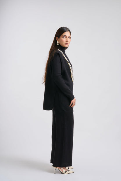 Woman wearing a black outfit with a high collar and long sleeves on a white background