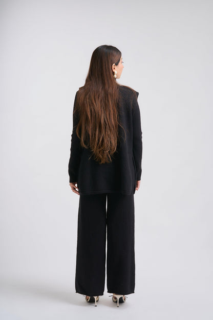 Person wearing a black outfit with wide-leg pants on a white background