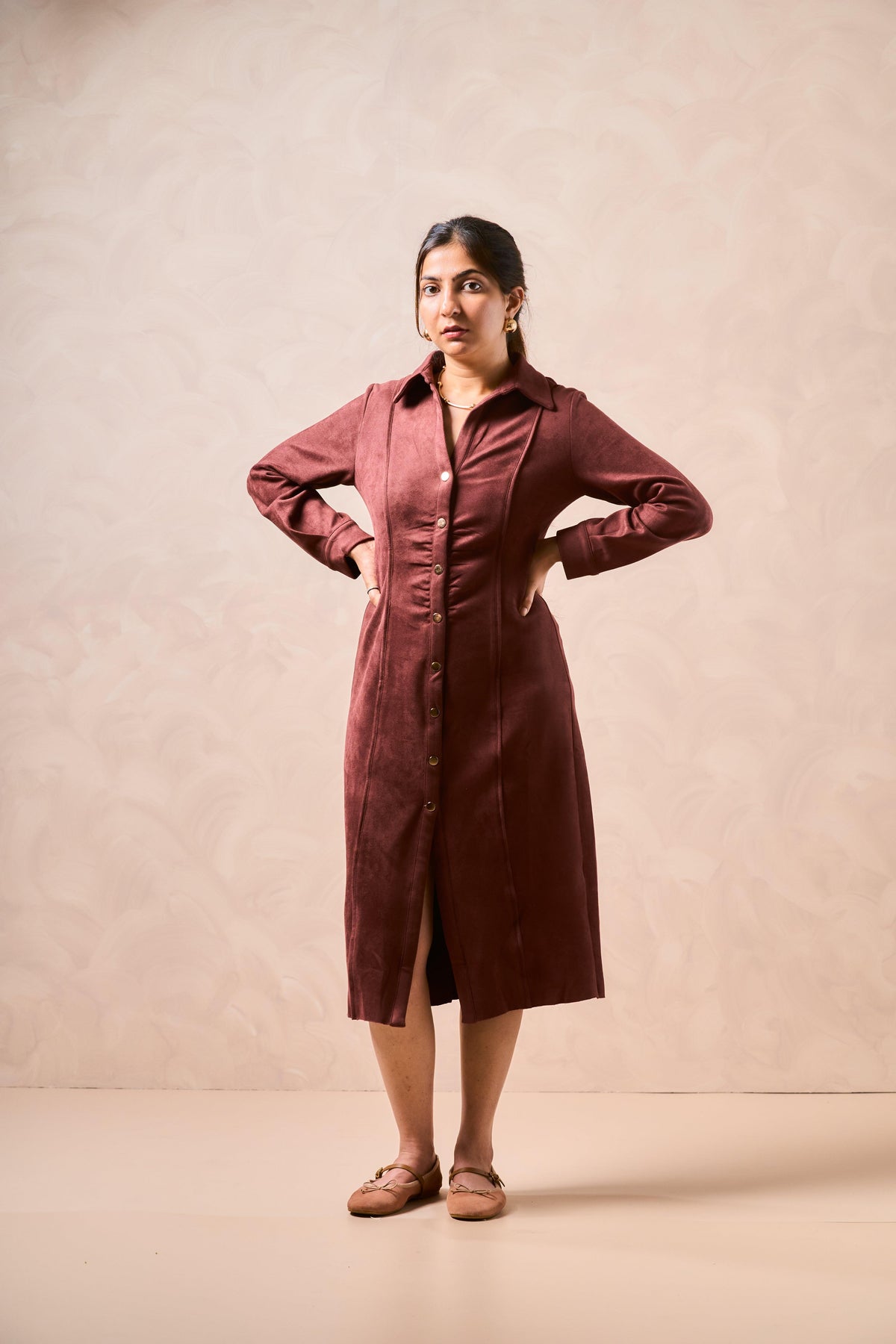 Woman wearing a burgundy dress against a beige background