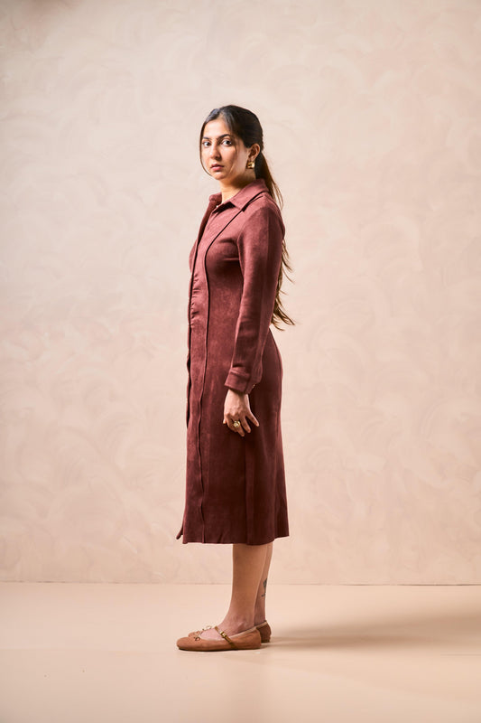 Woman wearing a long burgundy coat against a beige background
