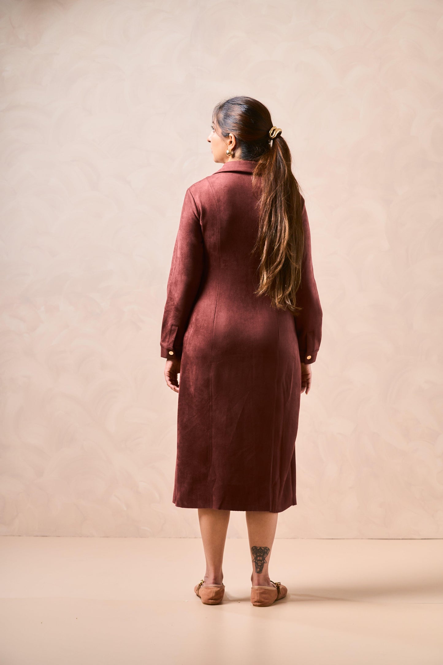 Woman wearing a burgundy dress against a beige background