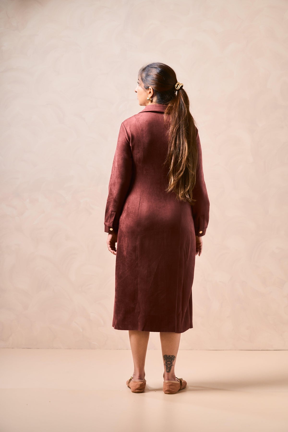 Woman wearing a burgundy dress against a beige background