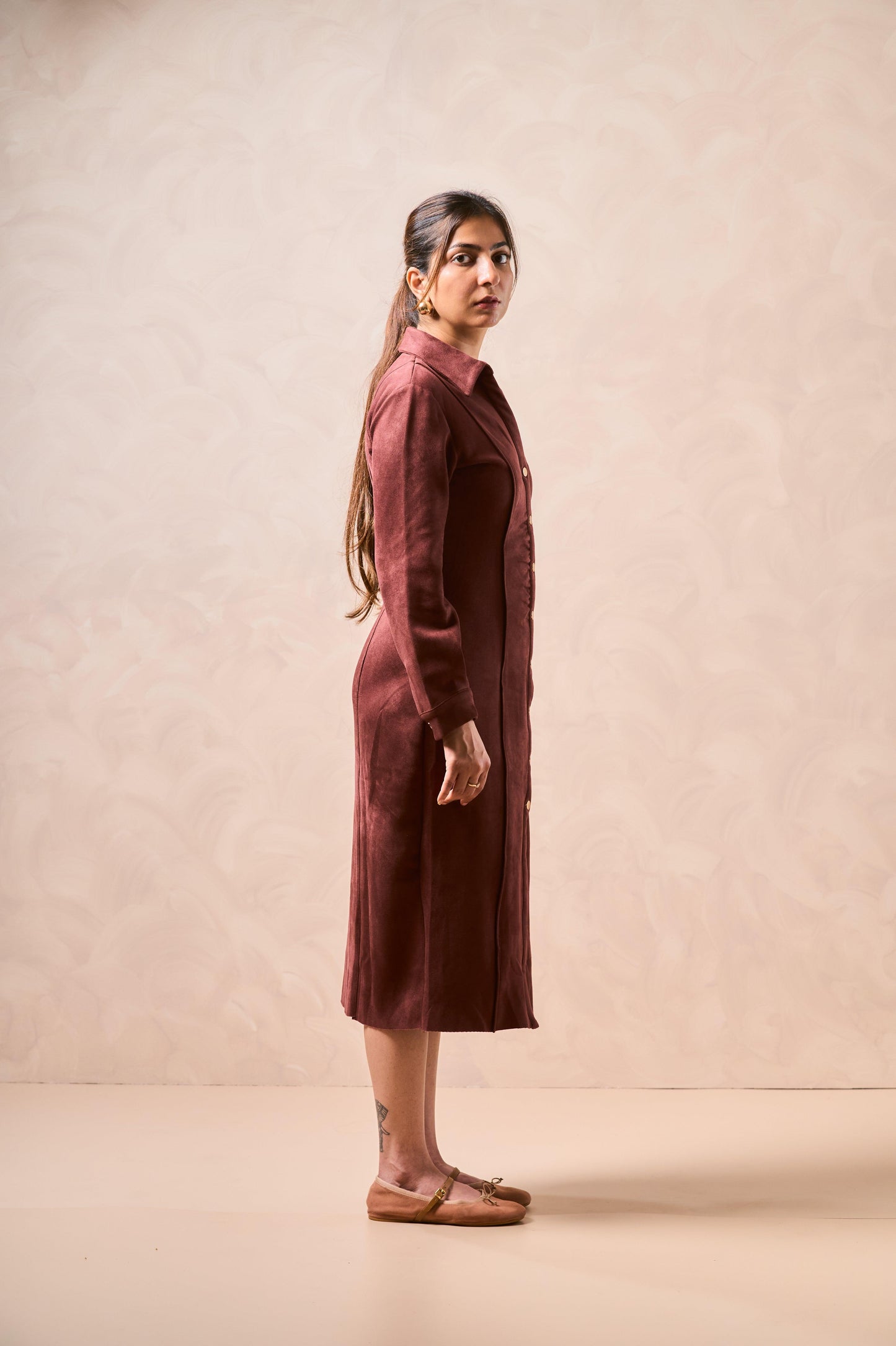 Woman wearing a burgundy dress against a beige background