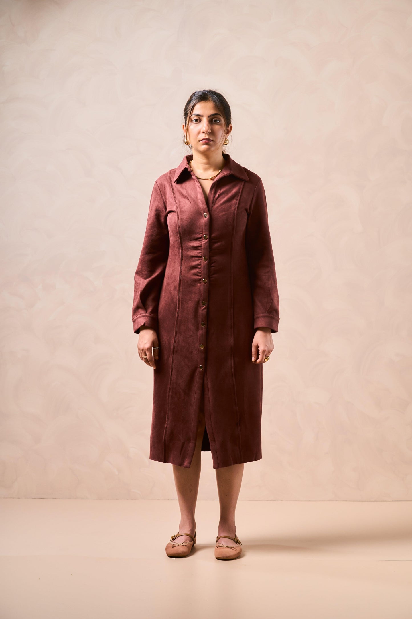 Woman wearing a brown dress against a beige background