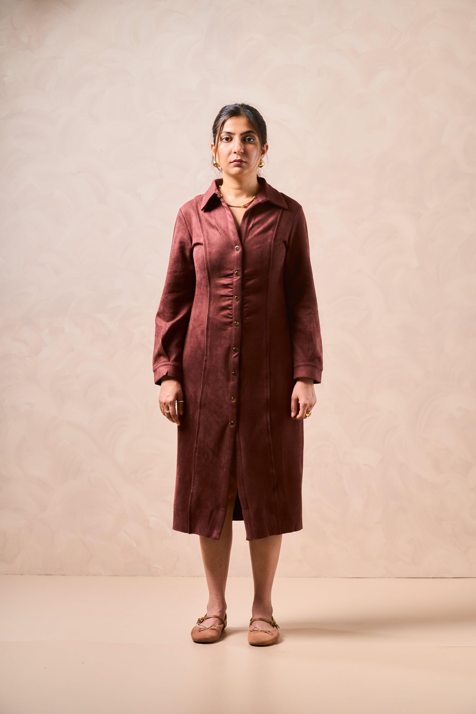 Woman wearing a brown dress against a beige background