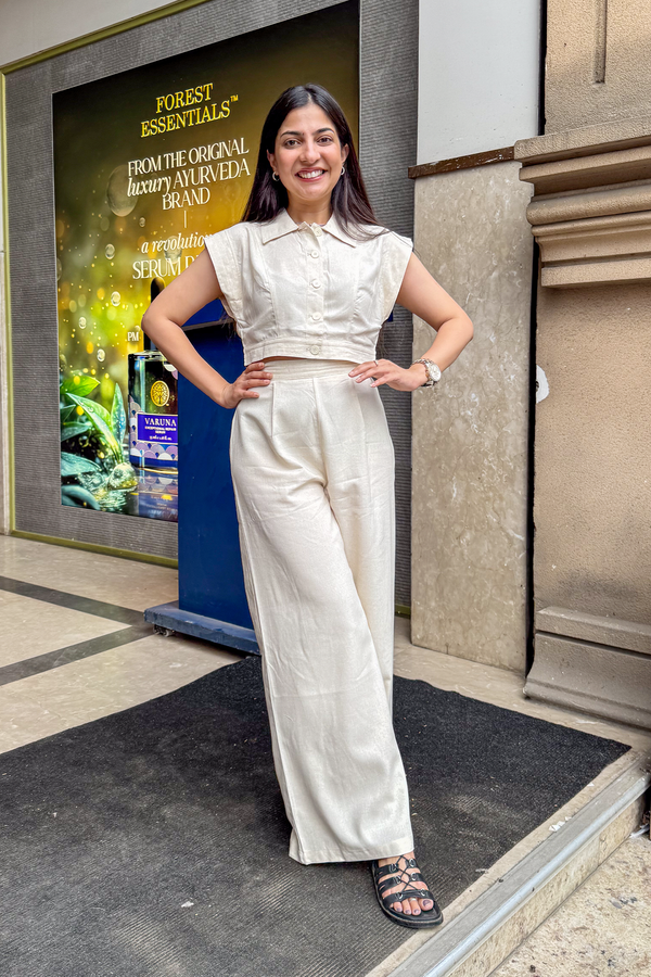 Woman in a white outfit standing in front of a Forest Essentials advertisement.