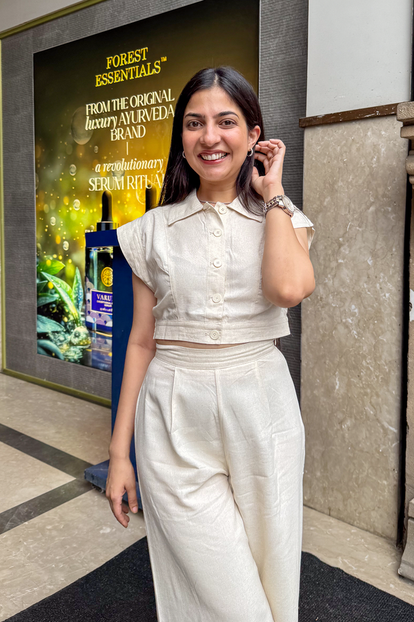 Woman in a white outfit standing next to a Forest Essentials advertisement