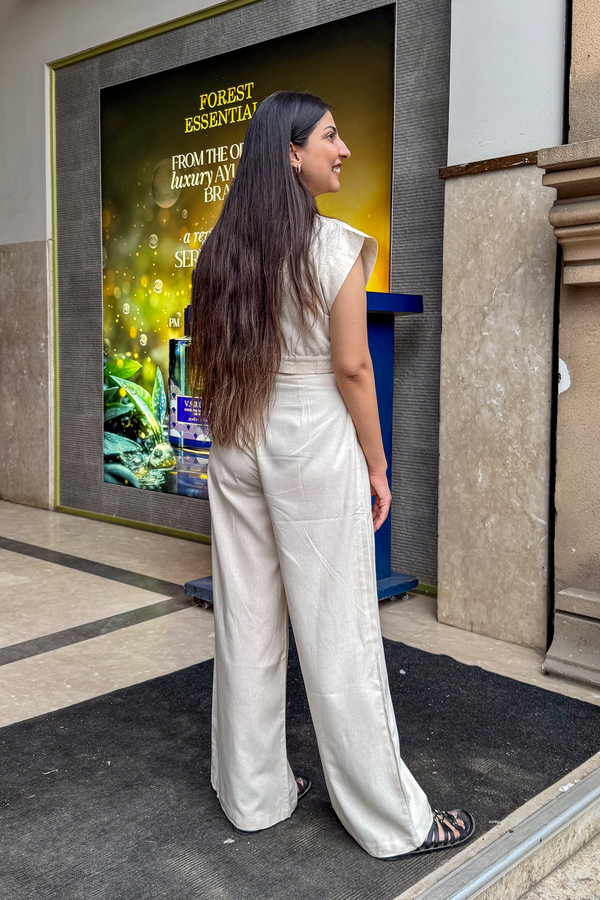 Woman in a white outfit standing in front of a large advertisement on a building wall.