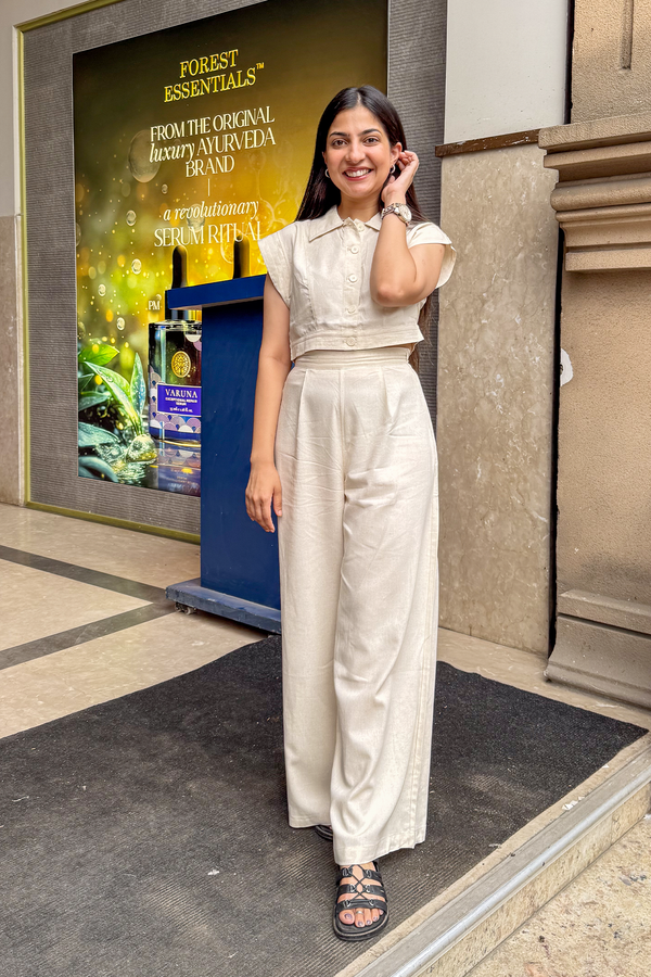 Woman in a white outfit standing in front of a store entrance with a visible advertisement.