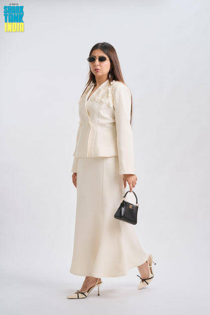 Woman wearing a white suit with sunglasses and a black handbag on a white background