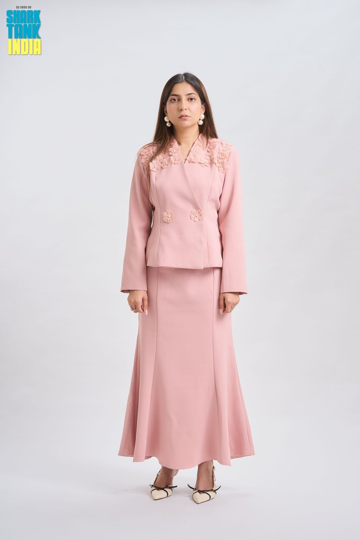 Woman wearing a pink suit with floral details on a white background