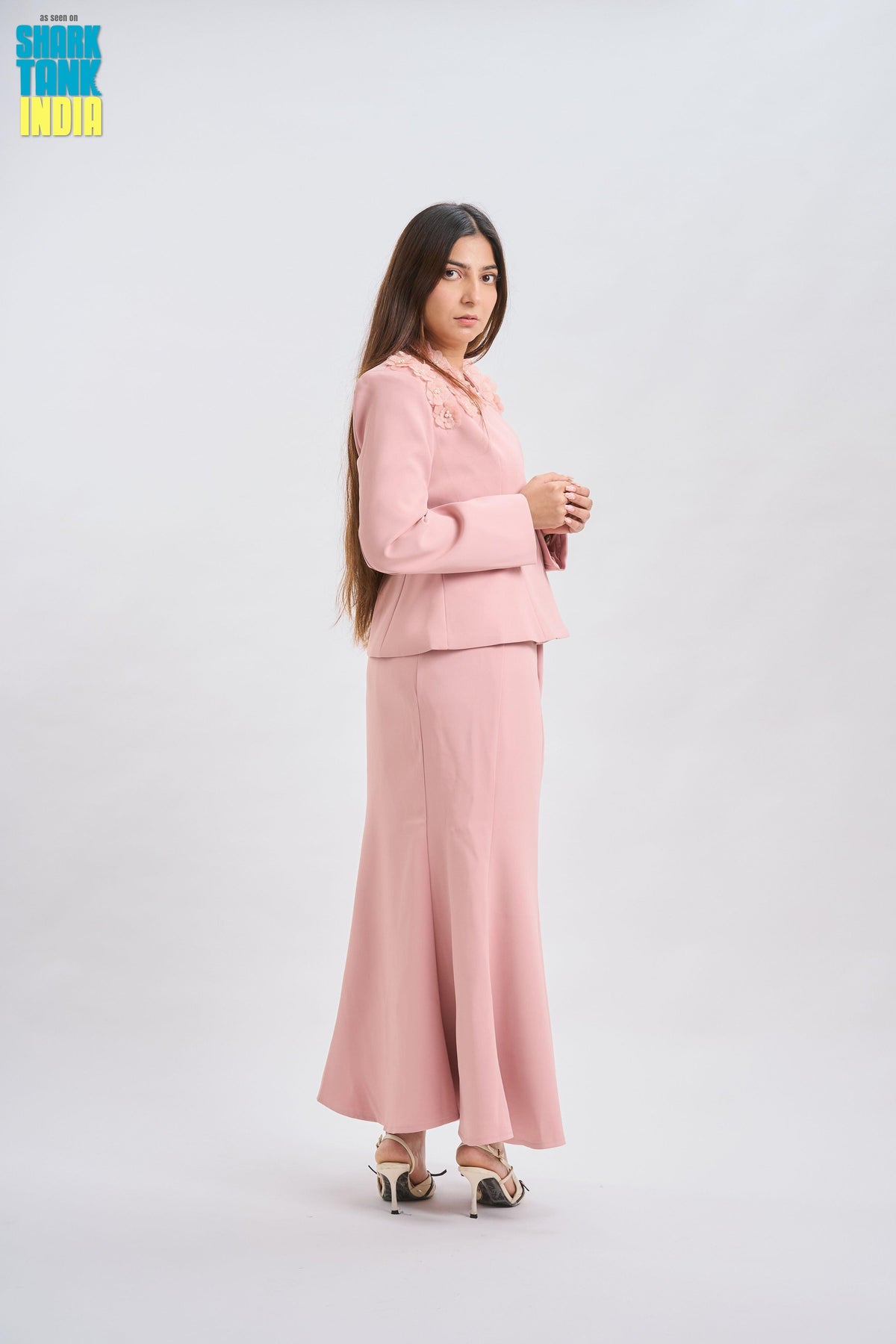 Woman wearing a pink suit standing against a white background