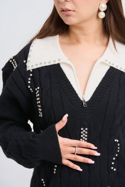 Person wearing a black cardigan with pearl embellishments on a light gray background