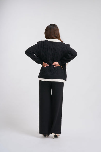Person wearing a black outfit with a white shirt on a plain background