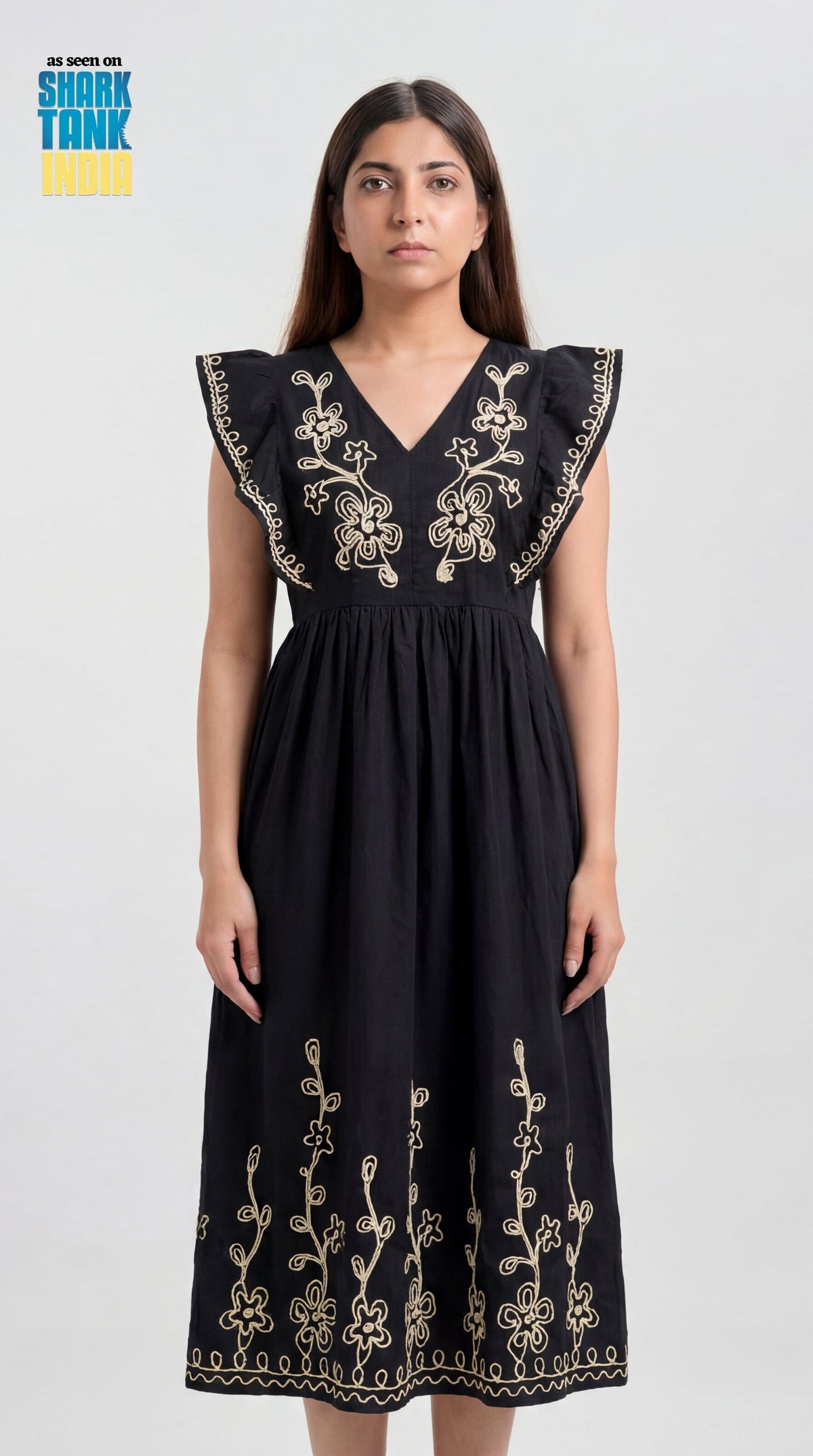 Woman wearing a black dress with gold embroidery on a white background