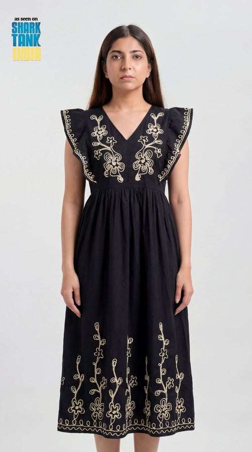 Woman wearing a black dress with gold embroidery on a white background