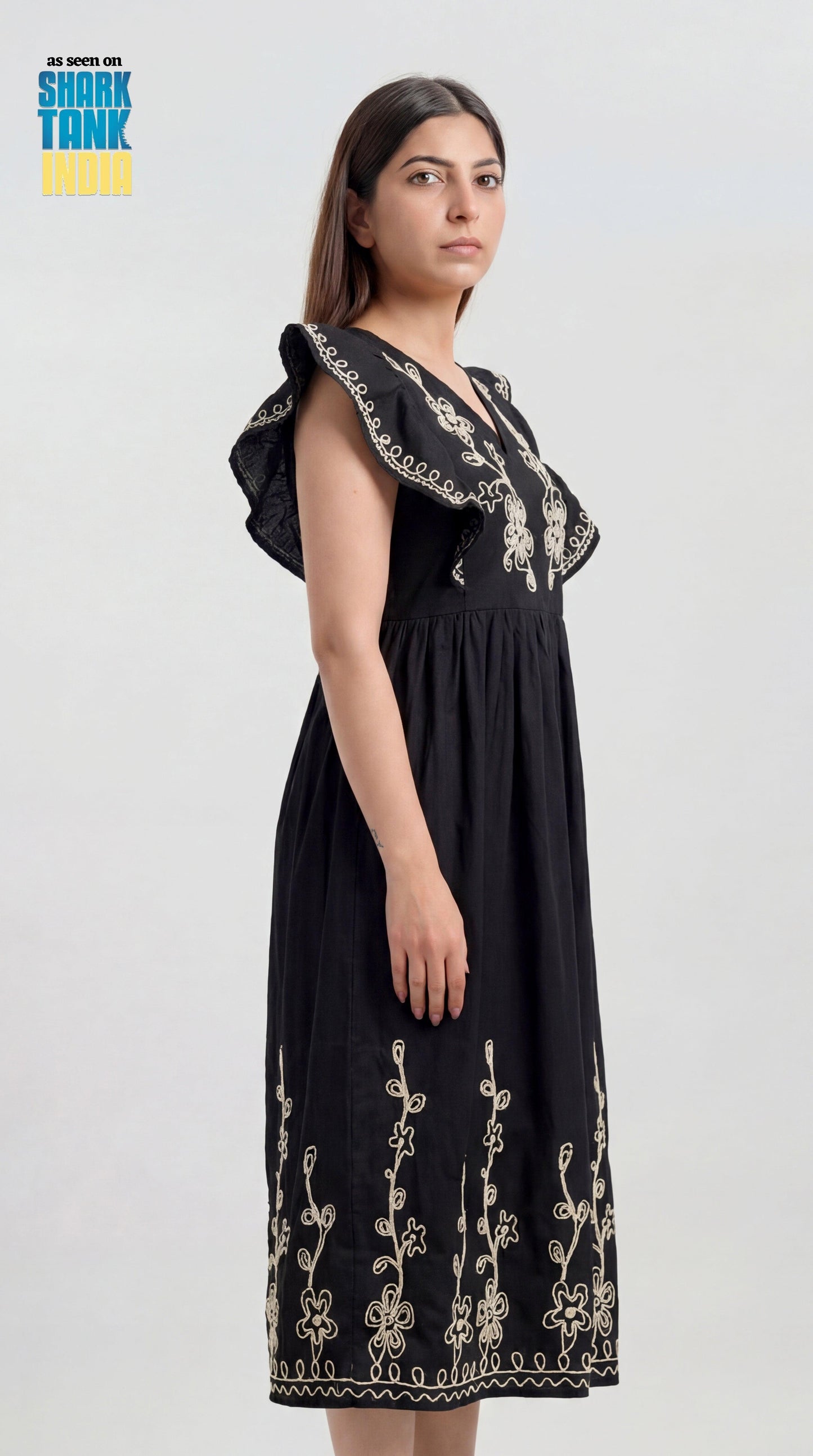 Woman wearing a black dress with floral embroidery on a white background